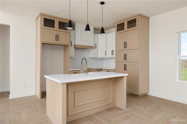 kitchen featuring light parquet floors, a kitchen island with sink, sink, and decorative light fixtures