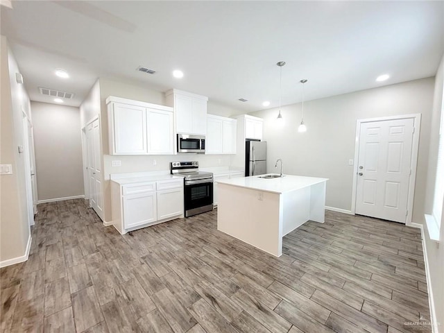 kitchen featuring pendant lighting, a center island with sink, sink, white cabinetry, and stainless steel appliances