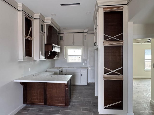 kitchen featuring stove, plenty of natural light, custom range hood, and white cabinets