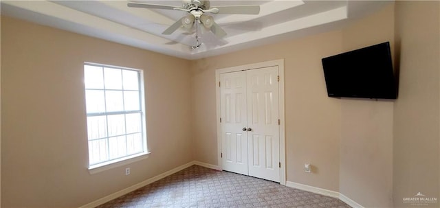 unfurnished bedroom featuring ceiling fan, a raised ceiling, and a closet