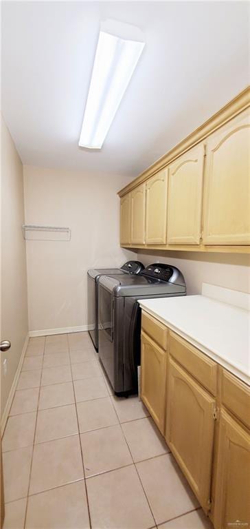 washroom featuring light tile patterned flooring, cabinets, and washing machine and clothes dryer