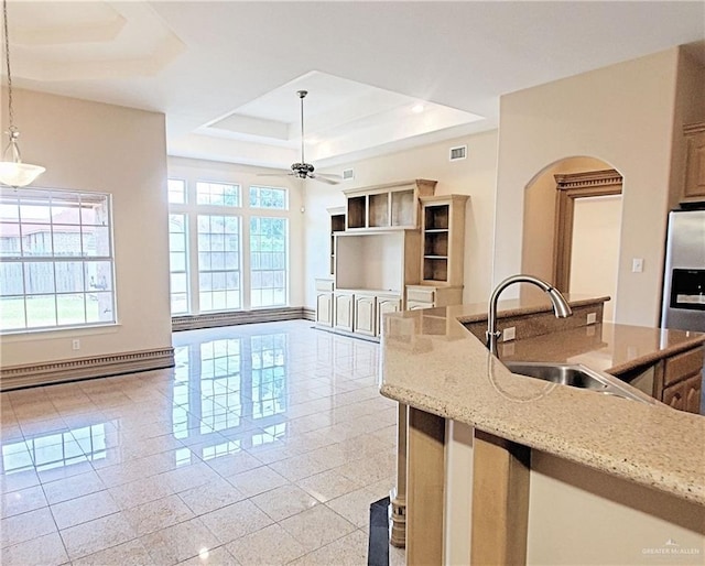 kitchen featuring light stone countertops, sink, stainless steel fridge with ice dispenser, a baseboard heating unit, and decorative light fixtures