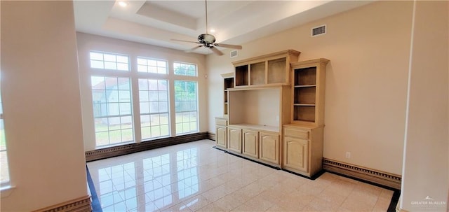 unfurnished living room with a tray ceiling, ceiling fan, and a baseboard radiator