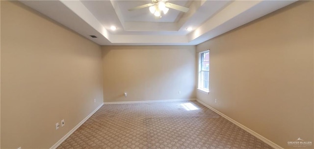 carpeted empty room featuring a tray ceiling and ceiling fan