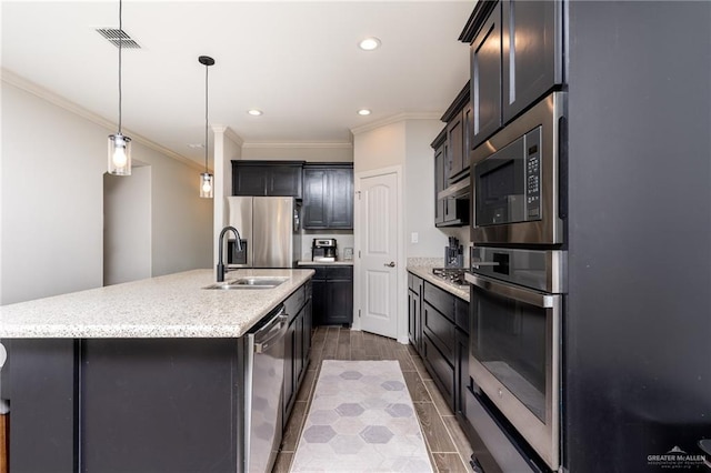 6101 White River Dr, Mcallen, TX 78504 - kitchen featuring crown molding, light stone counters, a sink, stainless steel appliances, and a center island with sink