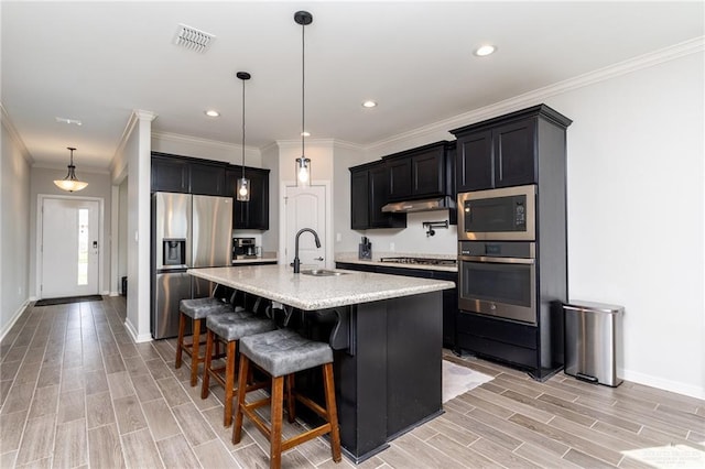 6101 White River Dr, Mcallen, TX 78504 - kitchen featuring appliances with stainless steel finishes, a sink, light wood-type flooring, under cabinet range hood, and visible vents