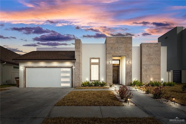 contemporary home with driveway, a garage, and stucco siding