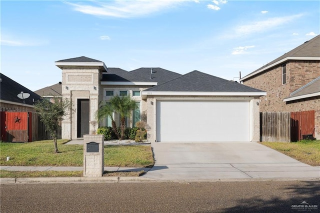 view of front of property with concrete driveway, a shingled roof, an attached garage, fence, and a front yard