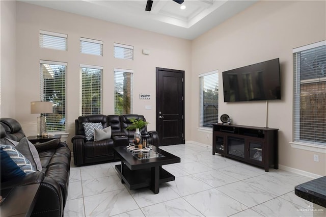 living area with marble finish floor, baseboards, a ceiling fan, and a towering ceiling