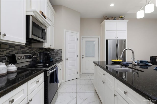 kitchen featuring white cabinets, marble finish floor, dark stone countertops, a sink, and appliances with stainless steel finishes