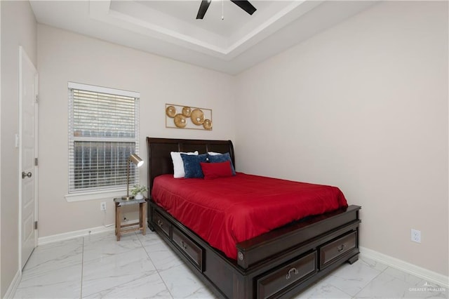 bedroom featuring marble finish floor, baseboards, a ceiling fan, and a tray ceiling