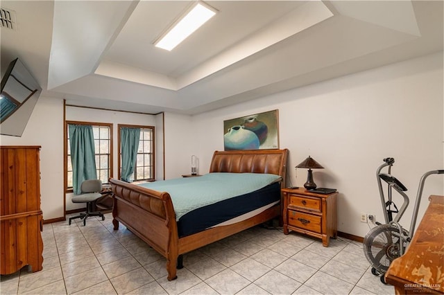 bedroom with light tile patterned floors, a tray ceiling, visible vents, and baseboards