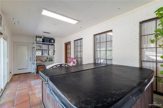 playroom featuring brick wall, ornamental molding, visible vents, and a healthy amount of sunlight