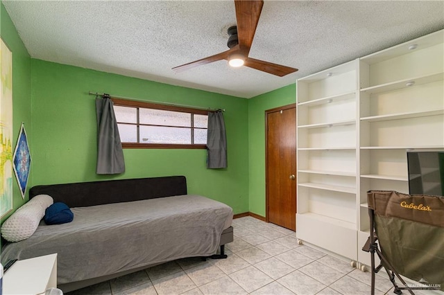 bedroom featuring baseboards, ceiling fan, tile patterned floors, a textured ceiling, and a closet