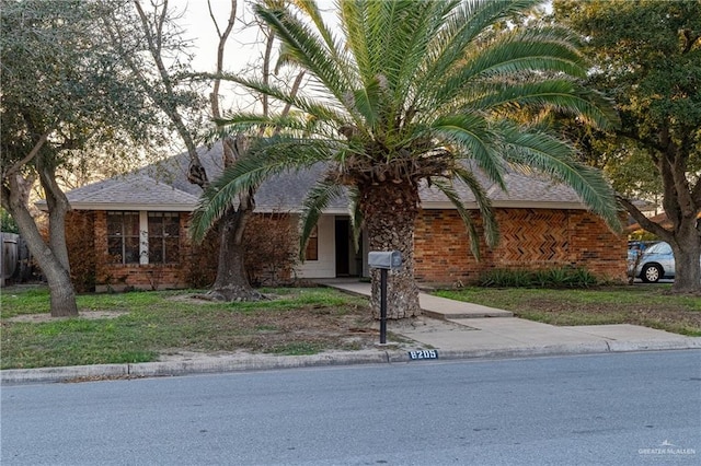 view of front of property featuring a shingled roof and brick siding