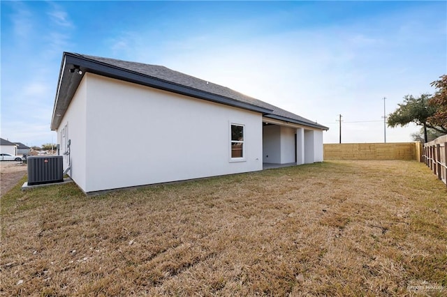 back of property with fence, cooling unit, and a yard