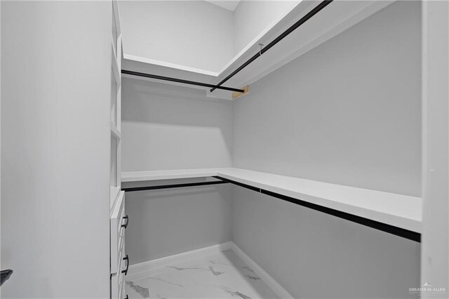 walk in closet featuring marble finish floor