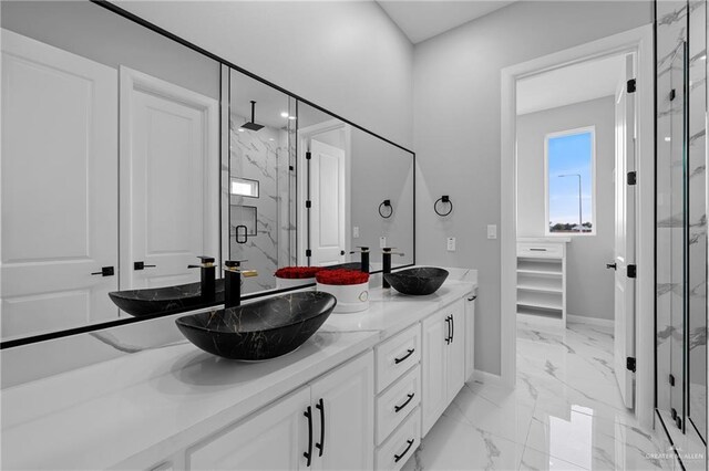 full bath featuring baseboards, a marble finish shower, marble finish floor, and a sink