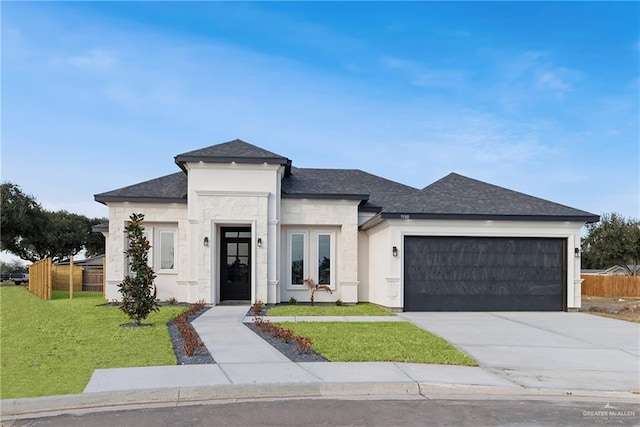 prairie-style home with concrete driveway, a shingled roof, a front yard, an attached garage, and fence