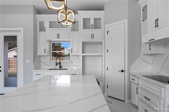 kitchen featuring white cabinets, black electric stovetop, marble finish floor, and a sink