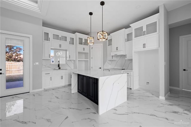 kitchen featuring marble finish floor, a sink, a kitchen island, and baseboards
