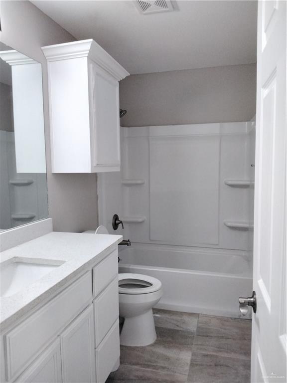 3018 Greenwood Dr, Corpus Christi, TX 78405 - full bath with toilet, visible vents, wood finished floors, and vanity