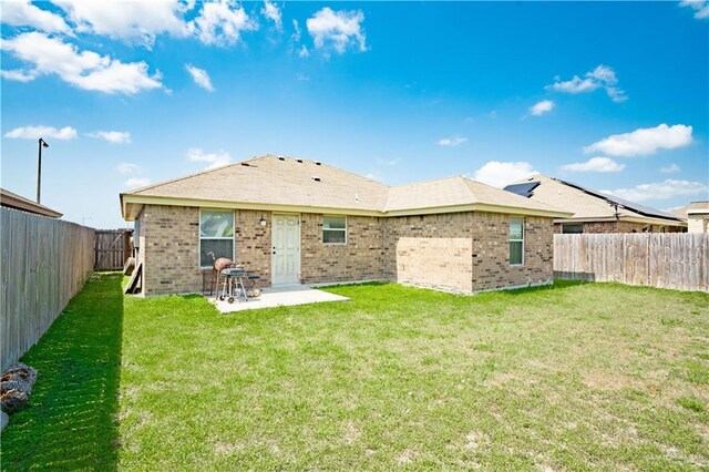 3292 Turquia St, Brownsville, TX 78520 - back of property with brick siding, a fenced backyard, a lawn, and a patio