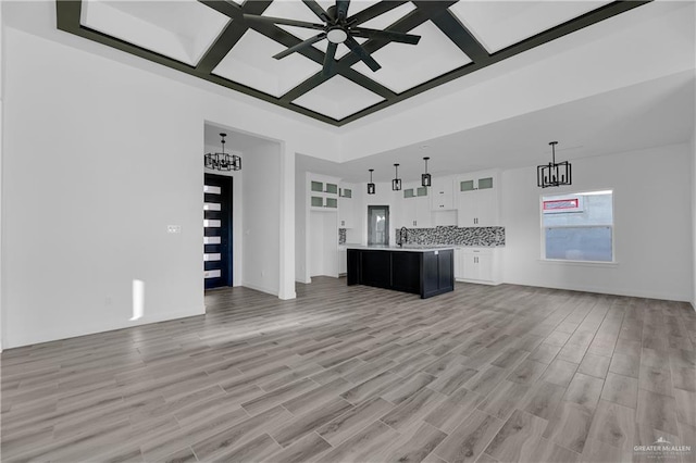 unfurnished living room with light hardwood / wood-style flooring, ceiling fan, coffered ceiling, and sink