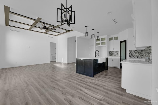 kitchen with white cabinetry, a kitchen island with sink, light hardwood / wood-style floors, and decorative light fixtures