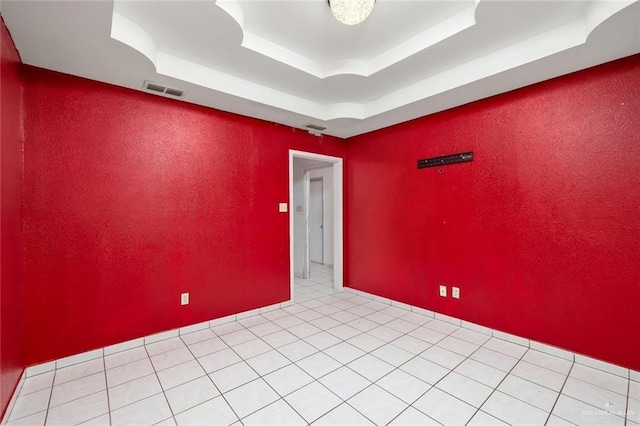 unfurnished room featuring light tile patterned flooring and a tray ceiling