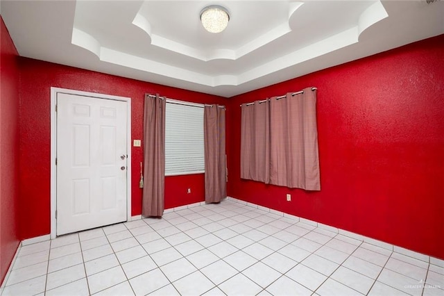 tiled empty room featuring a tray ceiling