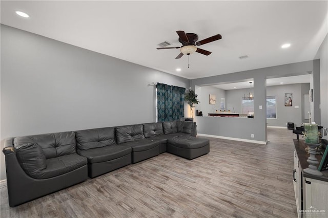 living room with wood-type flooring and ceiling fan with notable chandelier