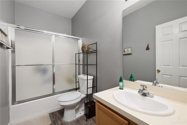 full bathroom with hardwood / wood-style flooring, vanity, toilet, and combined bath / shower with glass door