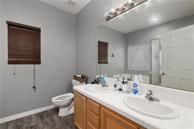 bathroom with hardwood / wood-style flooring, vanity, toilet, and a shower with shower door