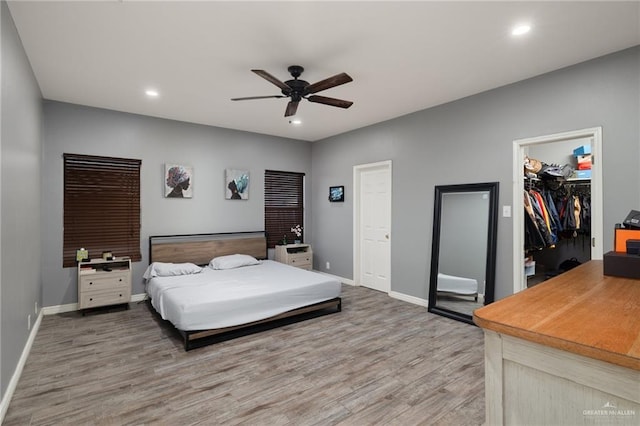 bedroom with ceiling fan, a walk in closet, and hardwood / wood-style floors