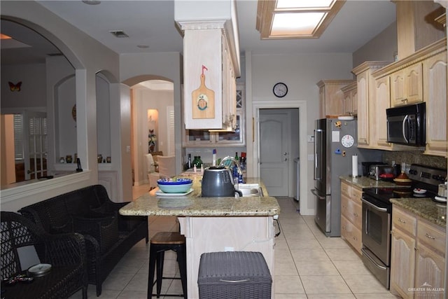 2707 Live Oak St, Mission, TX 78574 - kitchen featuring appliances with stainless steel finishes, a kitchen breakfast bar, tasteful backsplash, light tile patterned flooring, and light brown cabinets