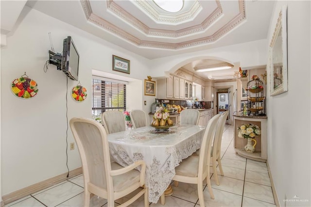 dining area with a raised ceiling, ornamental molding, and light tile patterned flooring