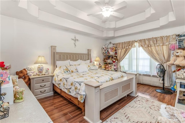 bedroom with a tray ceiling, ceiling fan, and dark wood-type flooring