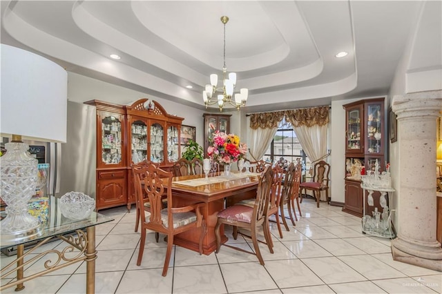 dining area with a raised ceiling, ornate columns, light tile patterned floors, and a notable chandelier