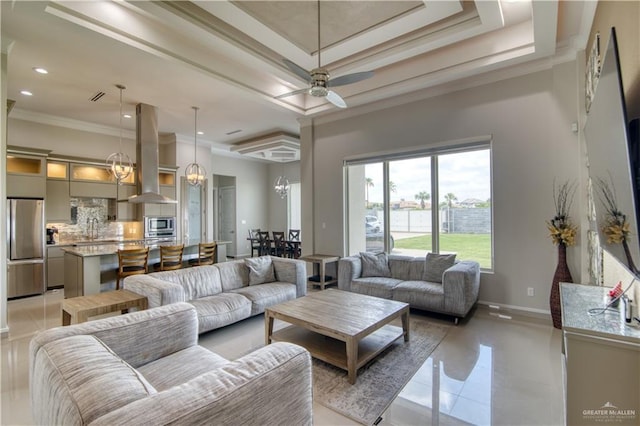 tiled living room featuring ceiling fan with notable chandelier, a raised ceiling, ornamental molding, and sink