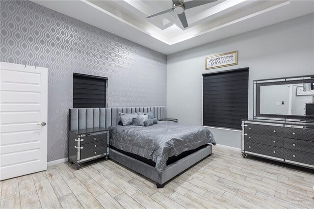 bedroom with a tray ceiling, ceiling fan, and light hardwood / wood-style floors