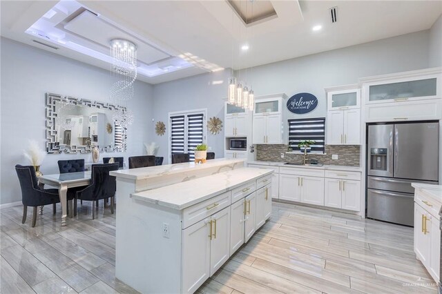 kitchen featuring hanging light fixtures, stainless steel appliances, a raised ceiling, and white cabinetry