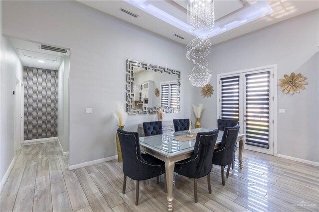 dining room featuring a tray ceiling, light hardwood / wood-style floors, and a notable chandelier