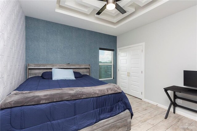 bedroom with a tray ceiling, ceiling fan, and light hardwood / wood-style floors