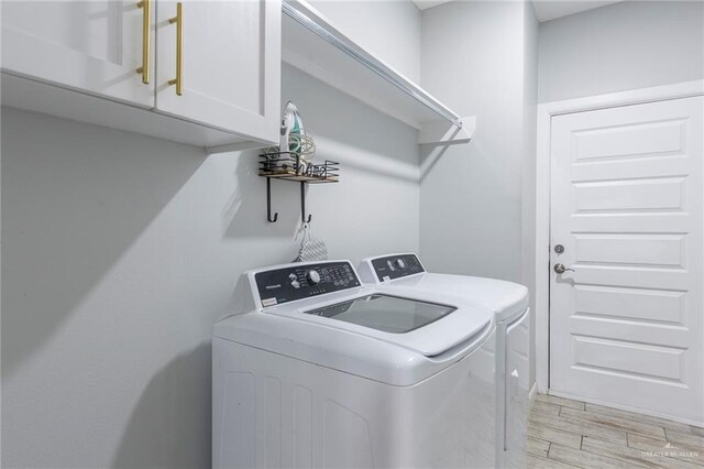 laundry room with washing machine and dryer, cabinets, and light hardwood / wood-style floors