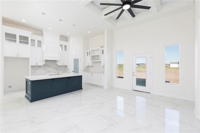 kitchen featuring sink, white cabinets, decorative light fixtures, an island with sink, and coffered ceiling