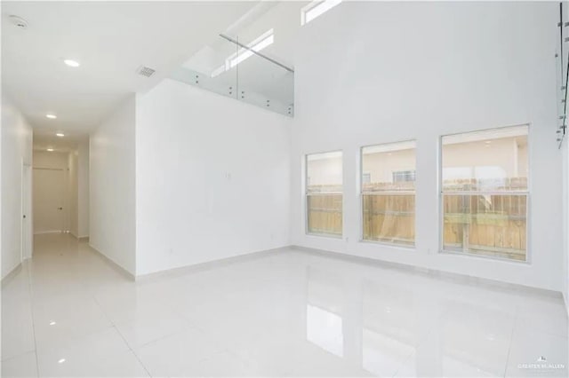 tiled spare room featuring a high ceiling