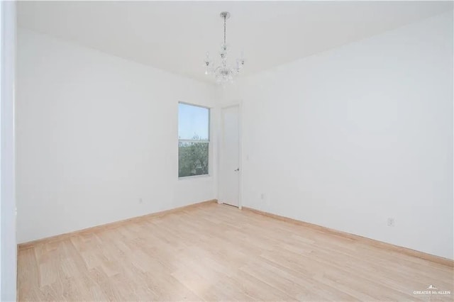 empty room with a notable chandelier and light hardwood / wood-style floors