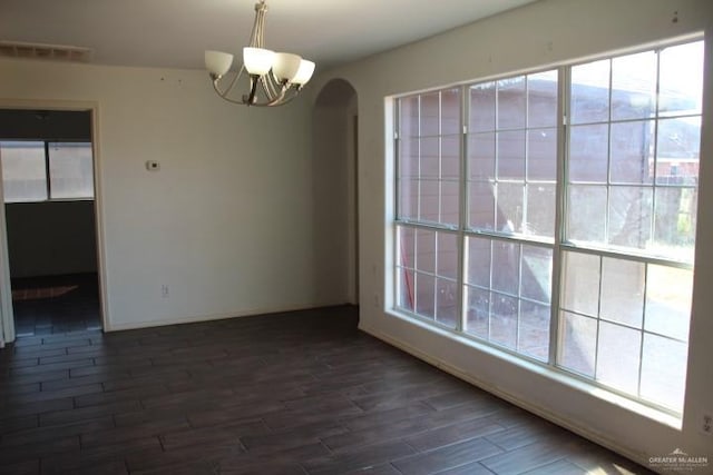 unfurnished dining area featuring plenty of natural light, dark wood-type flooring, and a chandelier