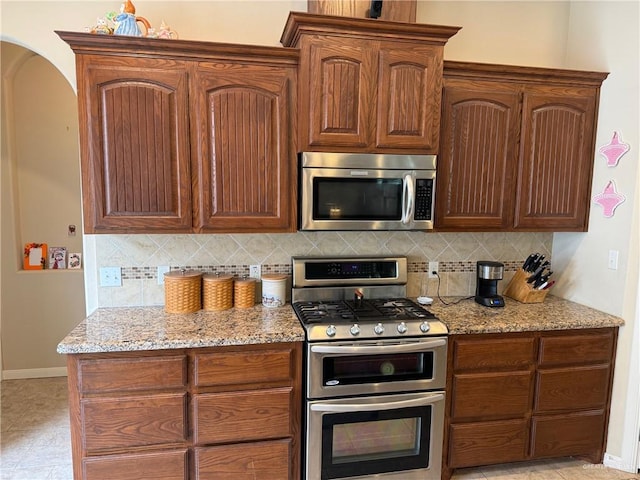 kitchen with light stone countertops, stainless steel appliances, and tasteful backsplash